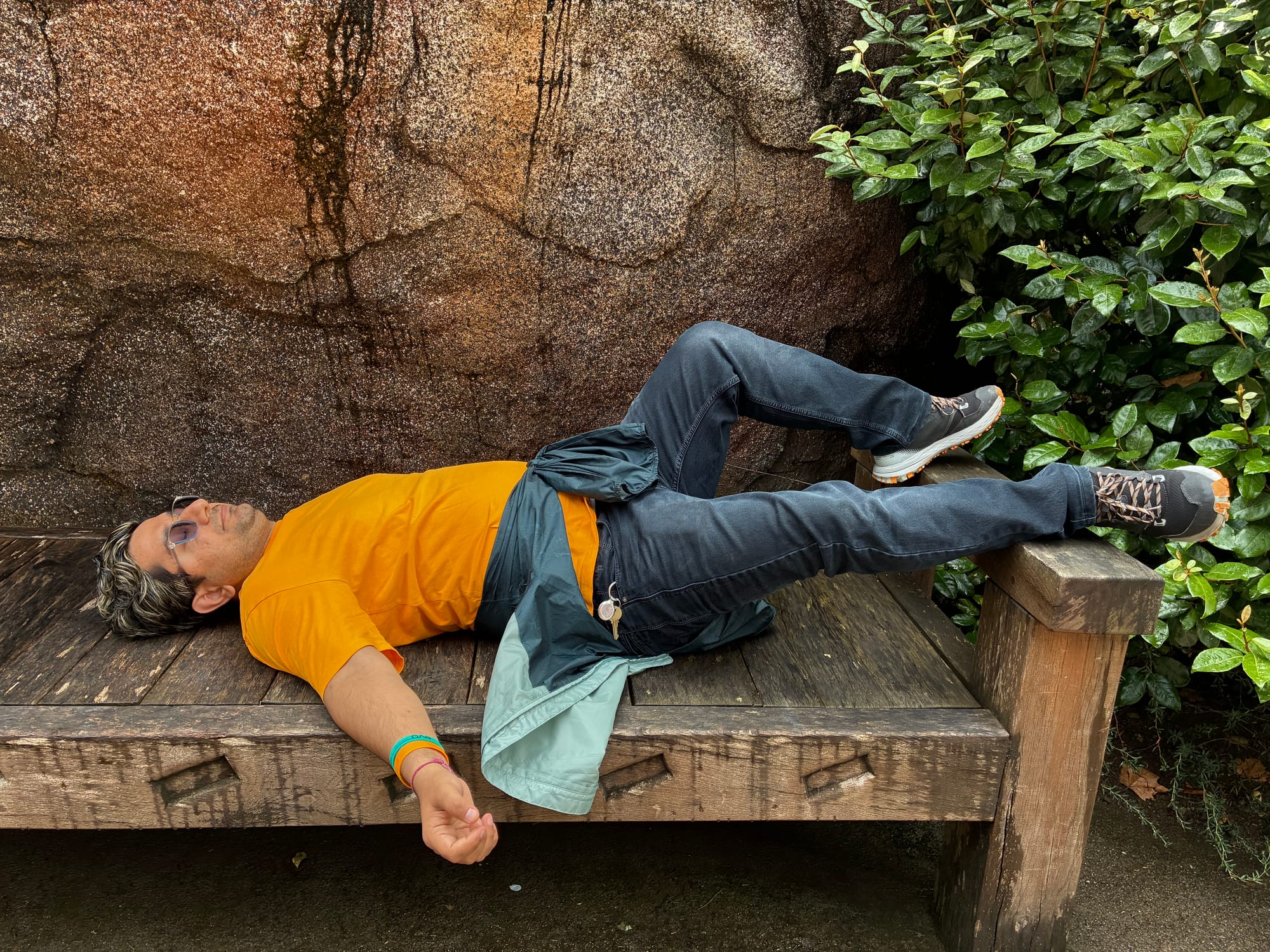 A person lying down on a wooden bench